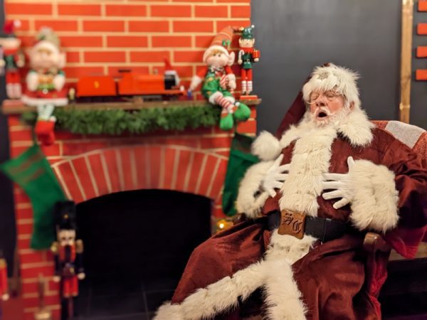 Father Christmas rubbing his belly, sat by the fire at Perrygrove Railway Adventure