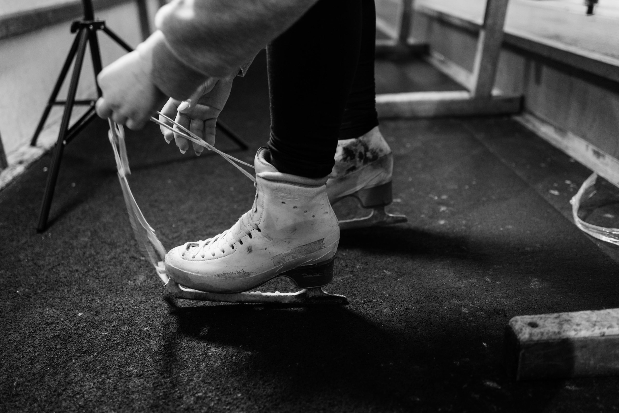 Close up of someone lacing up their ice skating boots on side of rink.